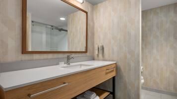 Une salle de bain moderne avec un meuble-lavabo en bois, un grand miroir et un espace douche.