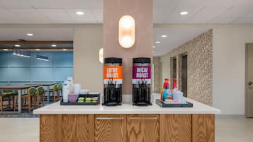 A coffee station with two coffee dispensers labeled 'Light Roast' and 'Decaf Roast' and a tray with disposable cups and condiments.