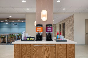 A coffee station with two coffee dispensers labeled 'Light Roast' and 'Decaf Roast' and a tray with disposable cups and condiments.