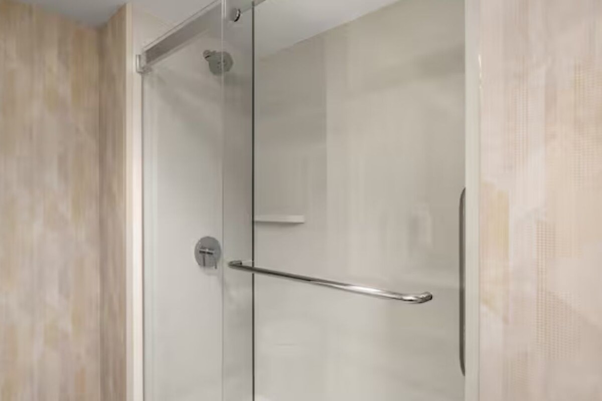 A glass-enclosed shower with a metal handle and a clear glass door.