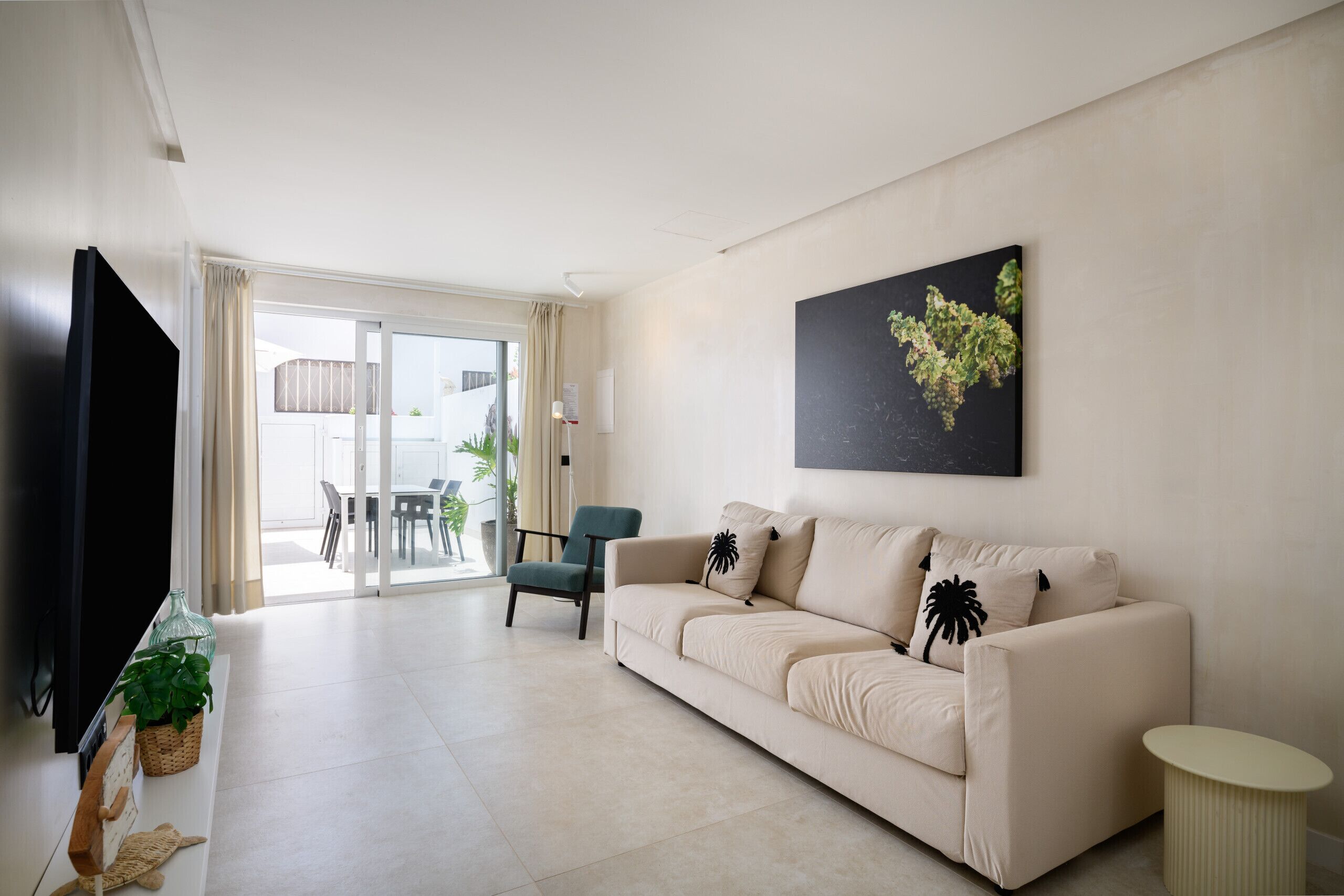 A modern living room with a sofa, a television, and a dining area with chairs and a table.