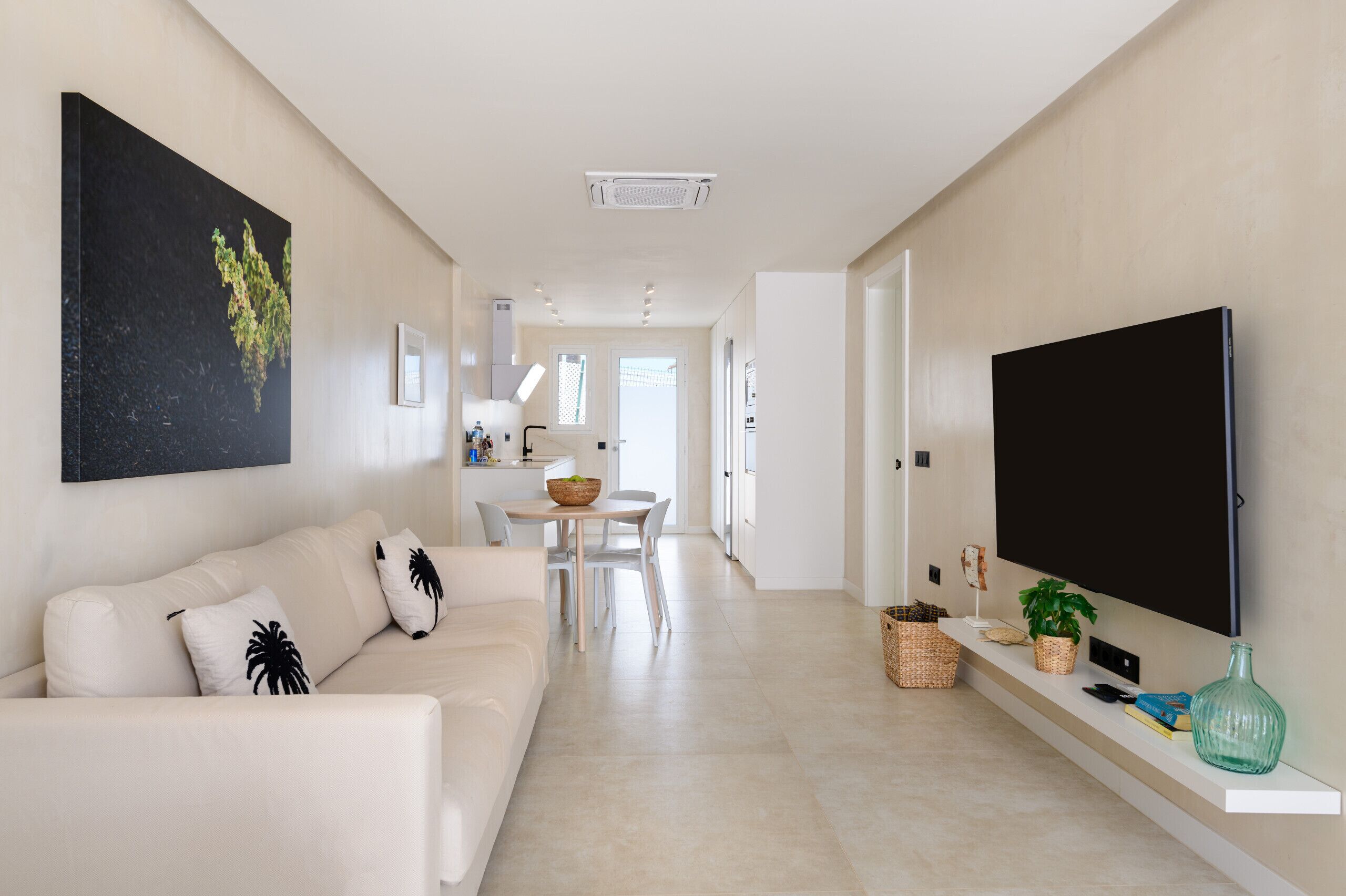 Un salon moderne comprenant un canapé, un téléviseur à écran plat et un coin repas avec une table et des chaises.