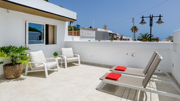 A rooftop terrace with white furniture, including chairs and a table, and a potted plant. - Casa Xabi, Private terrace - Puerto del Carmen (Puerto del Carmen)