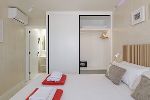 Een hotelkamer met een bed, een kledingkast, een nachtkastje, een hanglamp en een aan de muur bevestigd schilderij.