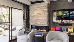 Una sala de estar moderna con chimenea, asientos cómodos y un televisor de pantalla plana mostrando una lista de reproducción de música.