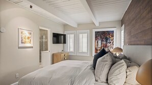 Un dormitorio con una cama grande, un aparador de madera, un televisor y obras de arte en las paredes.