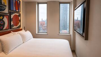 Una habitación de hotel con una cama grande, dos ventanas y obras de arte en las paredes.