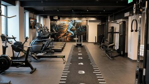 Un gimnasio con cintas de correr, máquinas de pesas y un mural motivador.