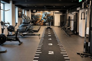 Un gimnasio con cintas de correr, máquinas de pesas y un mural motivador.