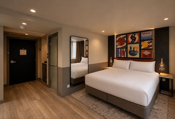Ein Hotelzimmer mit einem großen Bett, einem Spiegel, einem Nachttisch und Bildern an der Wand.