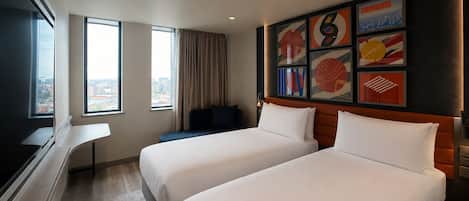 A hotel room with two beds, a large window, and a city view.