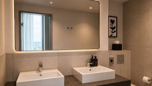 Un baño moderno con dos lavamanos, un espejo grande y un inodoro.