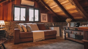 L’intérieur d’un chalet accueillant, avec un plafond en bois, un canapé agrémenté d’un plaid, une table basse et un mur en pierre.