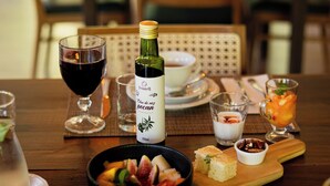 Une table à manger dressée avec différents plats, notamment une bouteille de vin, des verres et un saladier de fruits.