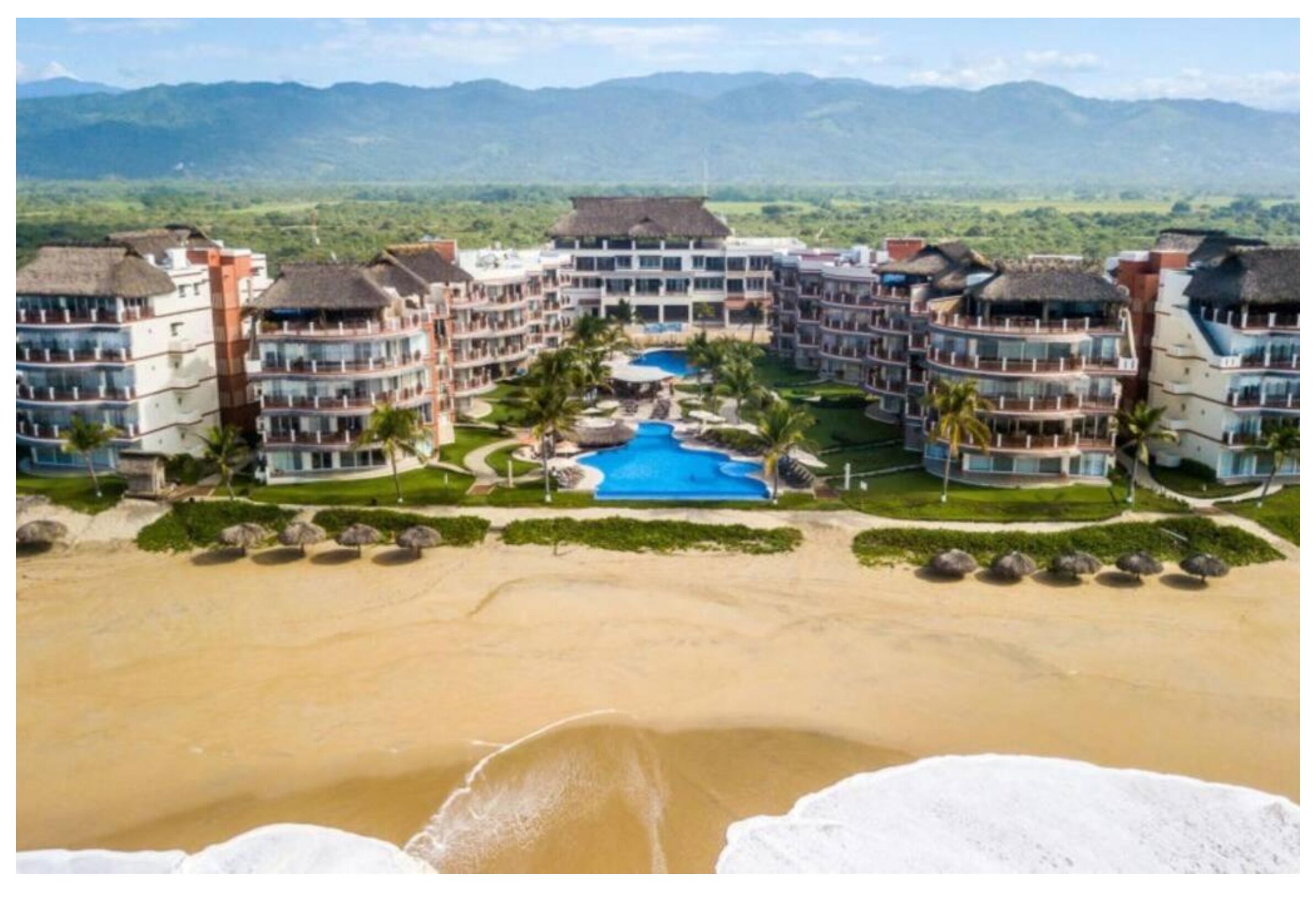 Un complexe hôtelier comprenant plusieurs bâtiments, une piscine et une plage.