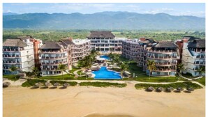 Um resort com vários edifícios, piscina e praia.