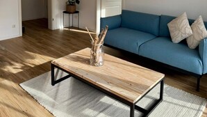 Ein Wohnzimmer mit einem blauen Sofa, einem Holztisch und einem Webteppich.