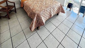 A bedroom with a bed, a chair, a window with blinds, and a ceiling light.