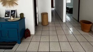 A spacious hallway with a blue cabinet, a woven basket, and a terracotta pot.
