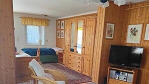 Kodikas huone, jossa on sohva, pieni pöytä, televisio ja puupanelointi.