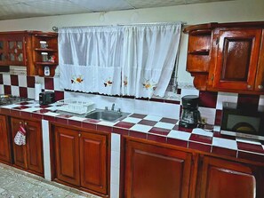 Eine Küche mit kariertem Fliesenspiegel, Holzschränken, einer Edelstahl-Spüle und einer Kaffeemaschine.