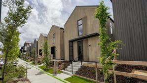 A modern residential building with a uniform architectural style, featuring a series of connected houses with external staircases leading to the entrance.