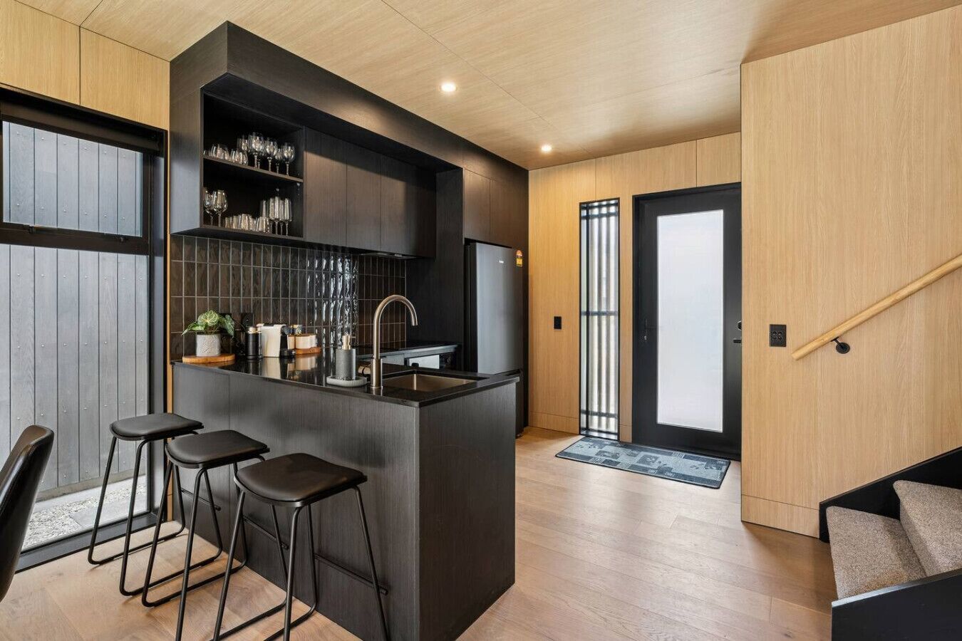 A modern kitchen with a central island, bar stools, and a built-in wine rack.