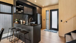 A modern kitchen with a central island, bar stools, and a built-in wine rack.