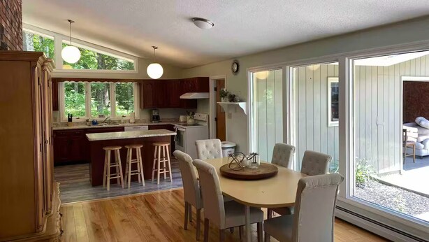 Una cocina moderna con una isla central, taburetes de bar y una mesa de comedor con sillas.