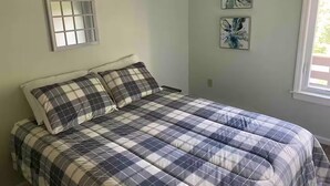 Un dormitorio con cama, una ventana y dos cuadros de flores en la pared.