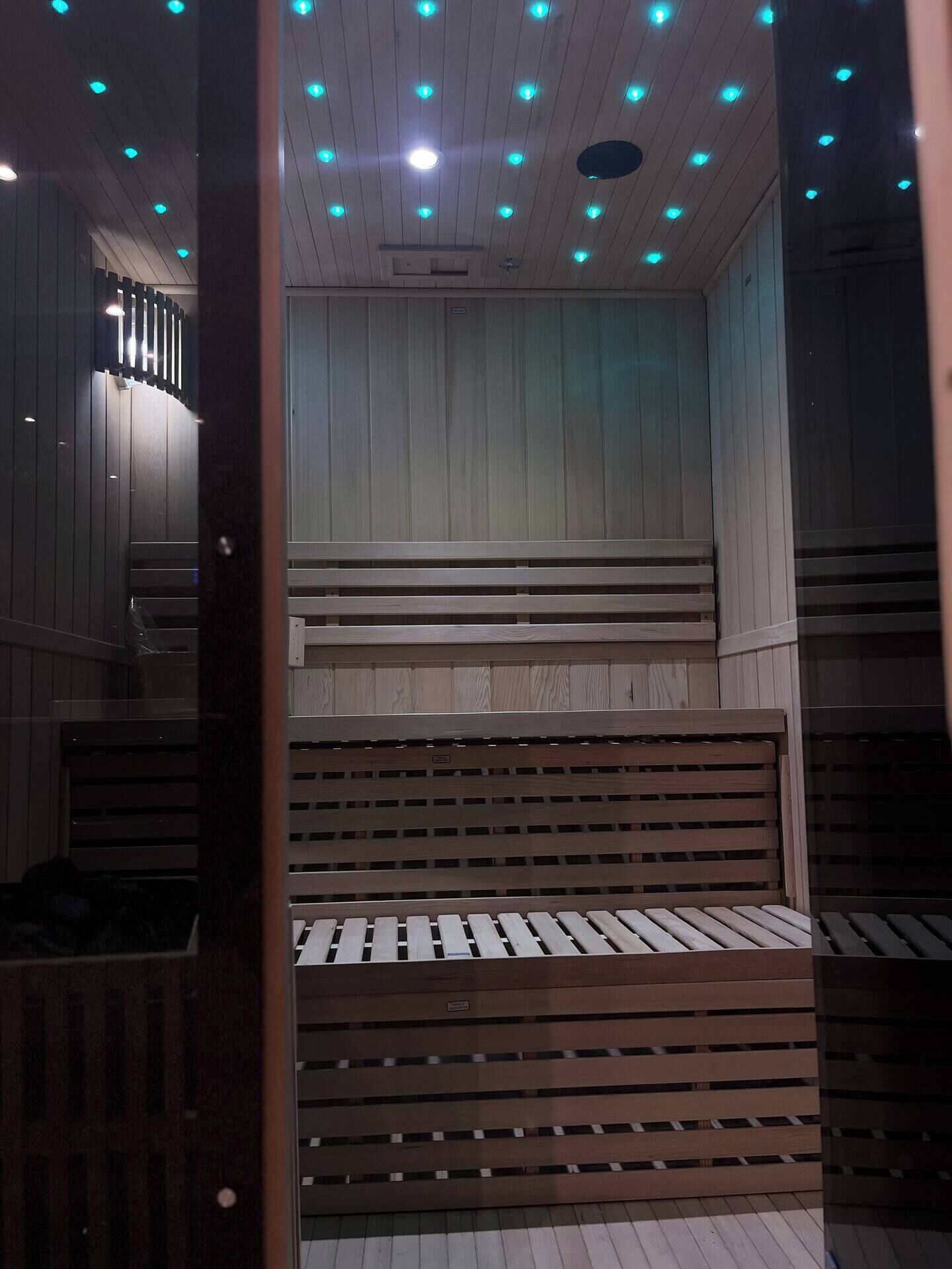 Een sauna met houten banken en een schuin dak met blauw licht.