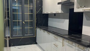 A modern kitchen with black and white cabinetry, a black countertop, and a marble floor. - Private luxury suite on 2 levels (Orly-sur-Morin)