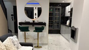 A modern living room with a sofa, a fluffy rug, and a round mirror above a bar area. - Private luxury suite on 2 levels (Orly-sur-Morin)