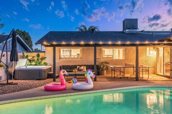 Ein Haus mit Pool, Sitzgelegenheiten im Freien und einer überdachten Terrasse.