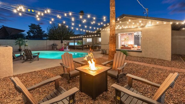 An outdoor patio with a pool, a fire pit, and string lights. - Resort Pool | Private Hot Tub | Close to Old Town (Scottsdale)