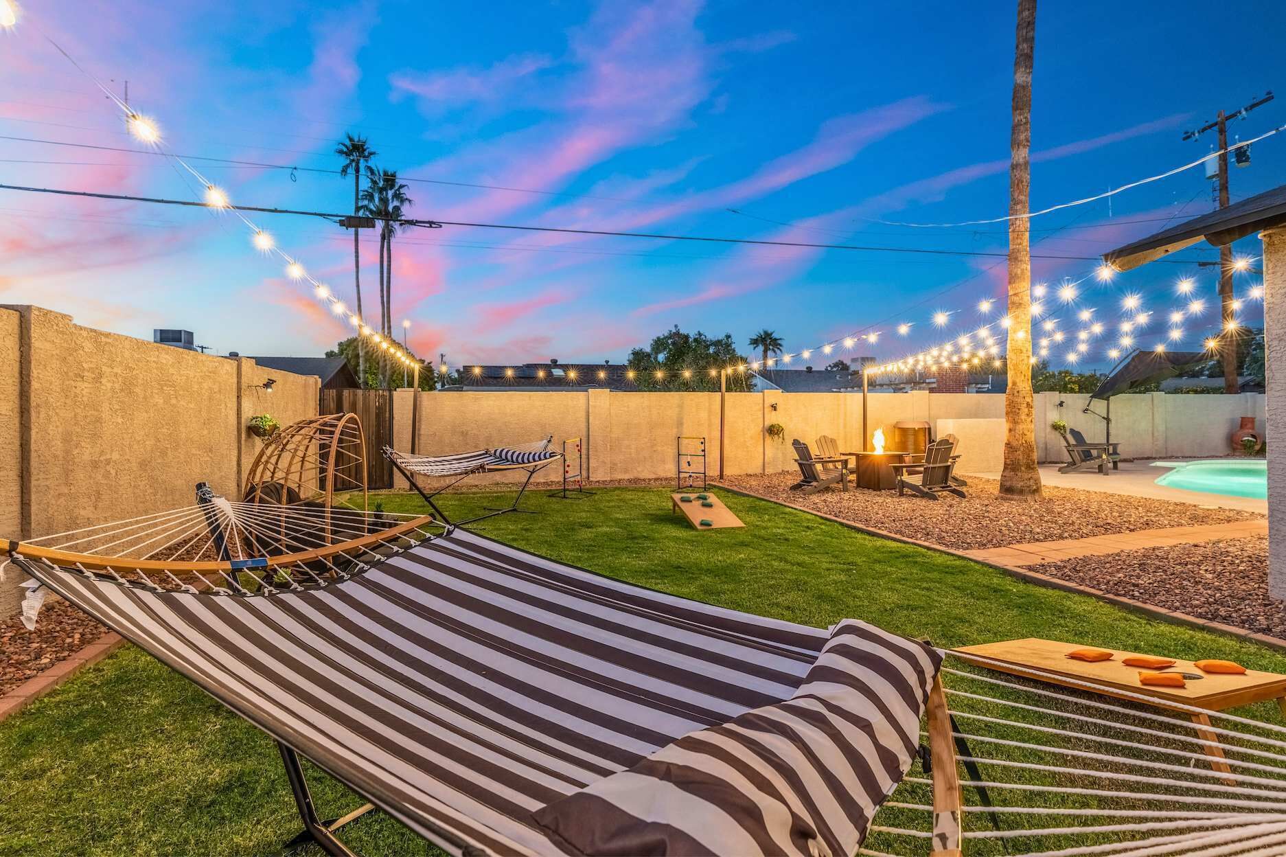A backyard with a hammock, a fire pit, and a pool.