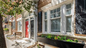 Une rangée de maisons de ville avec une porte rouge, des fenêtres blanches et une jardinière remplie de fleurs.