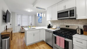 Une cuisine moderne avec des meubles blancs, des appareils en acier inoxydable et une table à manger en bois.