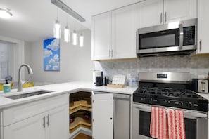 A modern kitchen with white cabinetry, a stainless steel microwave, a gas stove, and a built-in oven.
