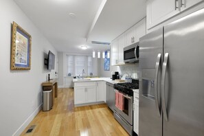 A modern kitchen with stainless steel appliances, white cabinetry, and a wooden floor. - Spacious 3BR Rittenhouse Retreat (Philadelphia)