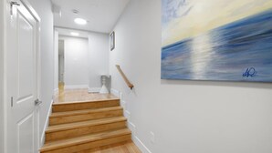 Un escalier avec des marches en bois menant à un palier, des murs blancs et un tableau accroché au mur.