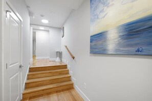 A staircase with wooden steps leading to a landing, white walls, and a painting on the wall. - Spacious 3BR Rittenhouse Retreat (Philadelphia)
