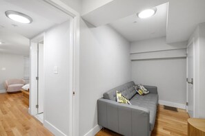 A modern living room with a grey sofa, a small armchair, and a wooden floor.