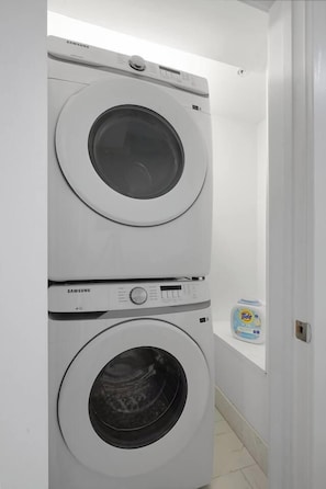 A stacked washer and dryer unit in a white-walled room.