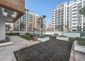 En modern bostadsbyggnad med flera balkonger, en vackert anlagd innergård och ett matområde.