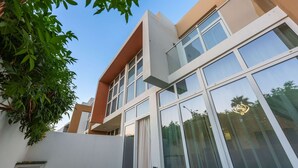 A modern building with large windows and a white facade. - Stayshort - Modern Villa in Avencia Damac Hills 2 With Waterpark Access (Dubai)