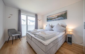 A bedroom with a bed, a chair, a painting, and a window. - Awesome apartment in OstseeResort Olpenitz (OstseeResort Olpenitz)