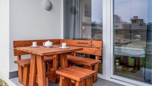 Un juego de banco y mesa de madera frente a un edificio con puerta de cristal.