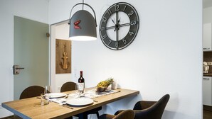 Un comedor con mesa de madera, sillas, un reloj de pared y una lámpara colgante.