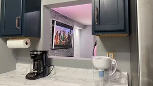 A kitchen with dark cabinets, a coffee maker, a clear mug, and a framed picture on the wall. - Downtown Harrisburg close to Hershey PA-Sleeps 8 (Harrisburg)
